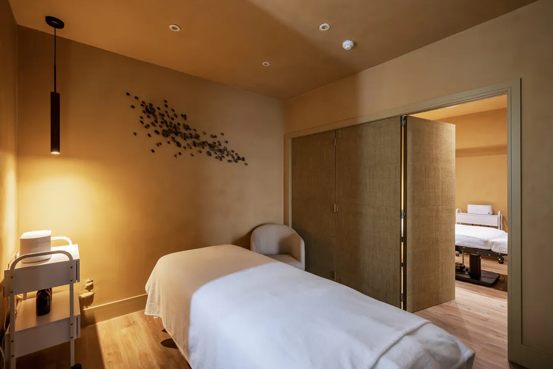 Spa treatment room with a massage bed and warm low lighting, Ilkley spa interior design by Dean Heim & Co.